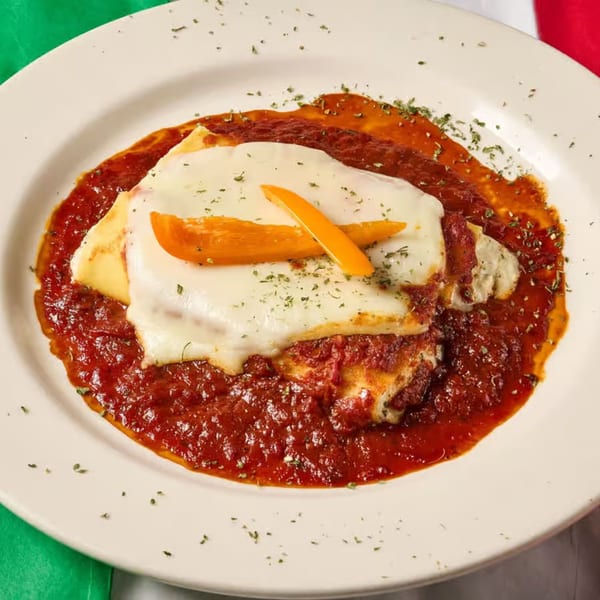 Lizzano's Pizza lasagna, topped with melted cheese, orange bell pepper strips, and dried herbs.