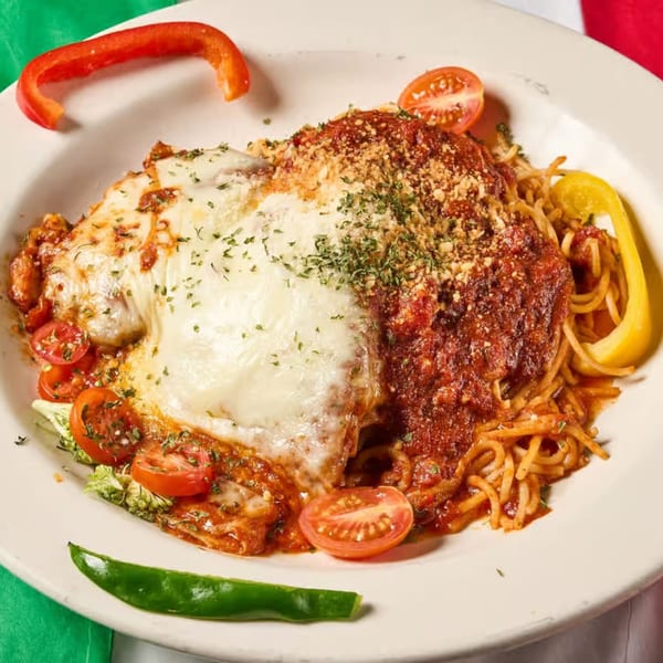 Chicken parmesan with melted mozzarella, marinara, spaghetti, and cherry tomatoes on a white plate.