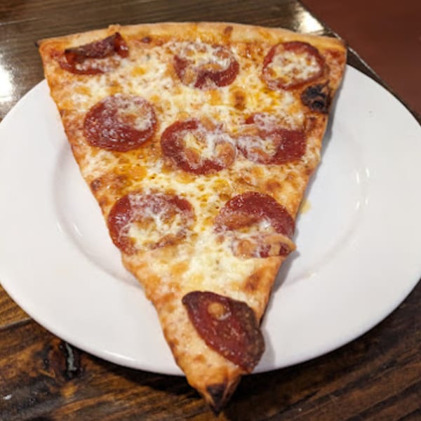 A single slice of Lizzano's pepperoni pizza with melted cheese on a white plate.