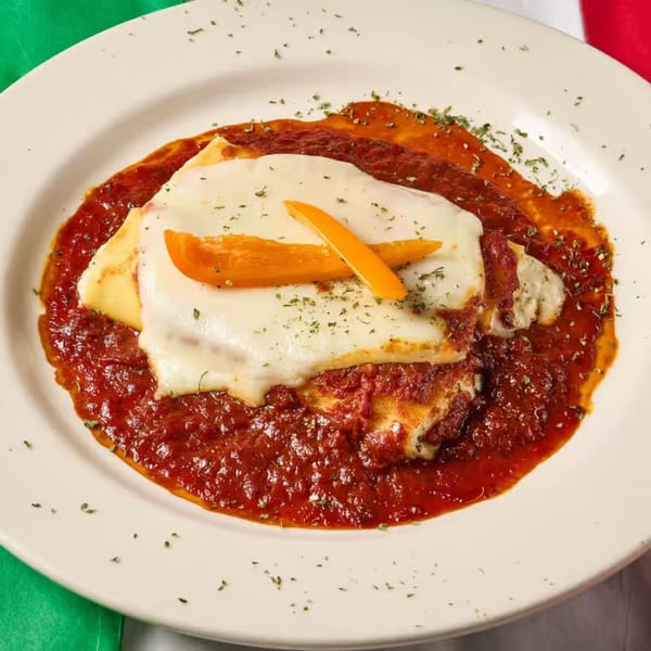 Lizzano's Pizza lasagna with melted cheese, rich red sauce, and orange bell pepper garnish.