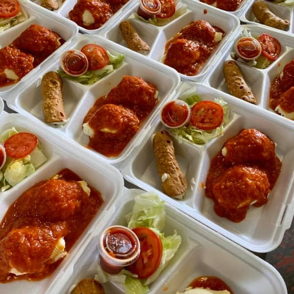 Multiple Lizzano's Pizza take-out containers with manicotti, side salad, and a cannoli.