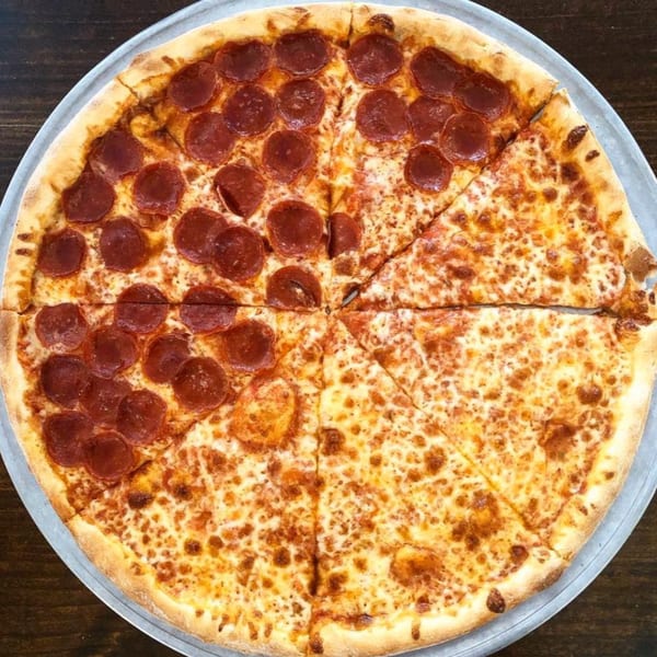 A large Lizzano's Pizza, half pepperoni and half cheese, on a metal pan.