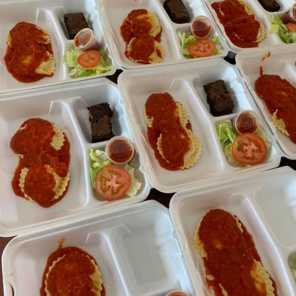 Multiple takeout containers with ravioli, marinara sauce, side salad, and a brownie.