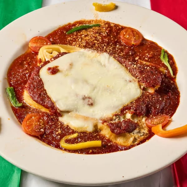 Lizzano's baked pasta dish with melted cheese, tomato sauce, cherry tomatoes, and bell peppers.