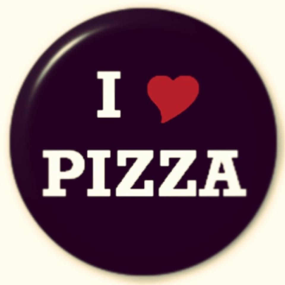 A circular button with "I (heart symbol) PIZZA" written in white text on a dark background.